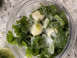 bowl with cilantro, garlic cloves, salt, salsa verde ingredients