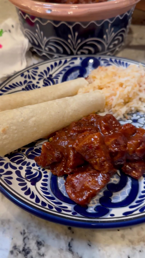 pork dish on a plate with tortillas and rice